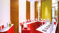 A corner view of the Senate conference room at Pride Plaza Ahmedabad, featuring rows of chairs with red covers, suitable for seminars or large presentations.